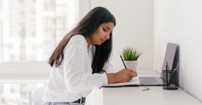 Relógio Pomodoro ao lado de laptop e caderno em mesa, pronto para sessão de escrita