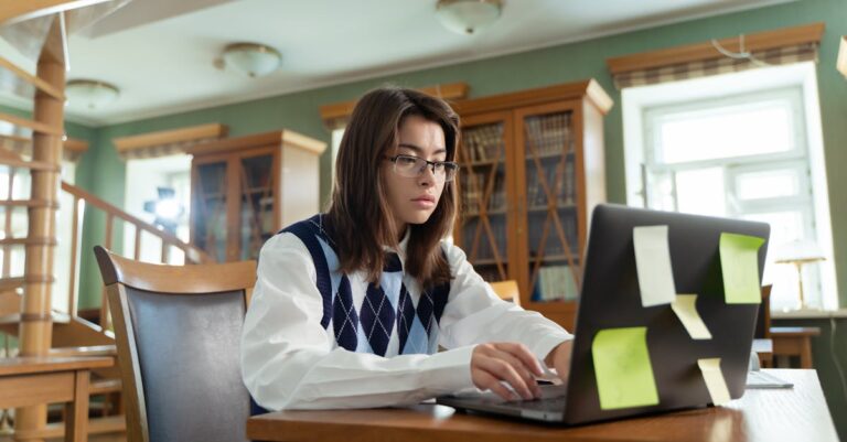 Pessoa em sessão de apoio com orientador, laptops e anotações em mesa de biblioteca