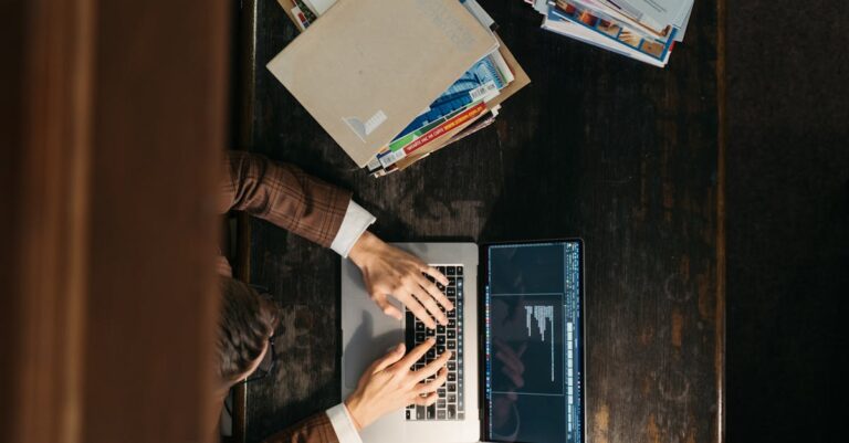Mãos escrevendo rascunho de pré-projeto com livros e laptop ao redor, foco na estrutura e viabilidade.