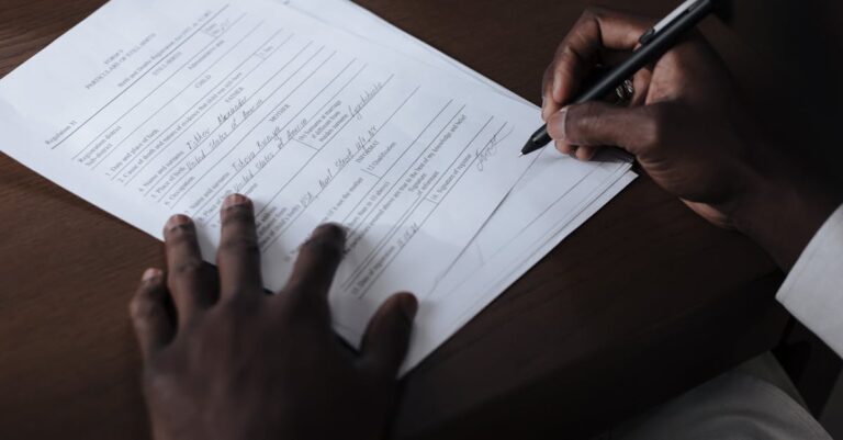 Mãos assinando formulário de autoria sobre prancheta com documentos ao redor