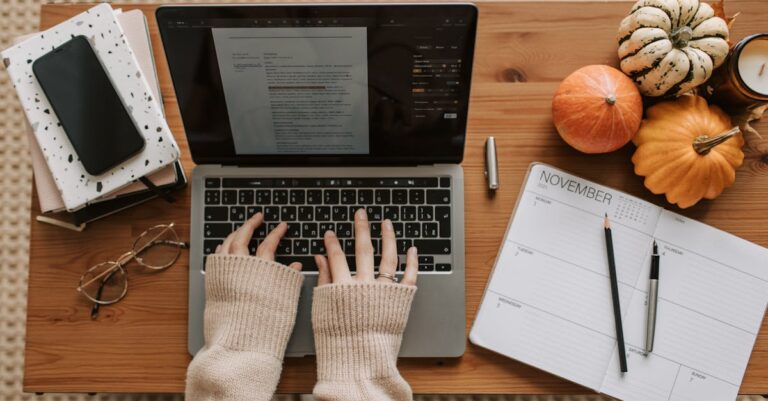 Laptop com calendário e checklist de prazos sobre mesa, mãos digitando.