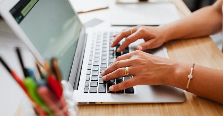 Mãos preenchendo formulário em laptop com tela do sistema borrada