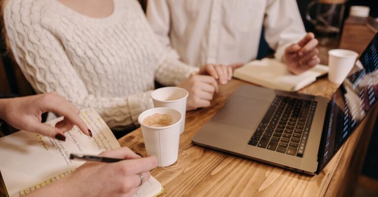 Mãos de duas pessoas sobre caderno e laptop durante uma sessão de responsabilidade mútua