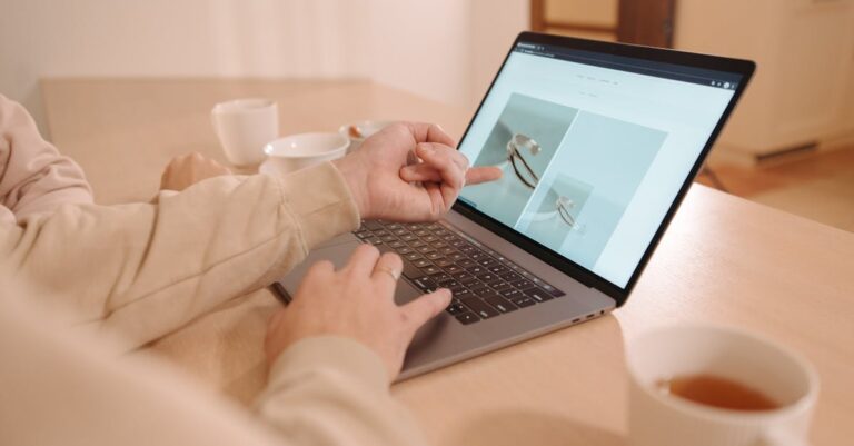 Mãos apontando para gráficos e tabelas na tela do laptop durante revisão de análises