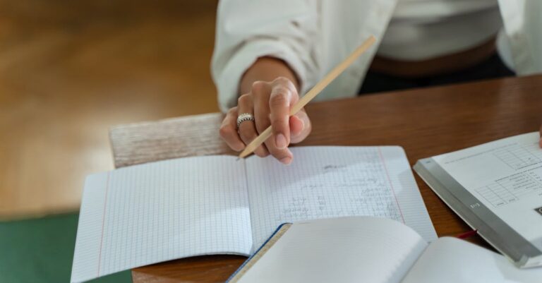 Aluno consultando opções de bolsas no celular, caderno com anotações sobre financiamento ao lado