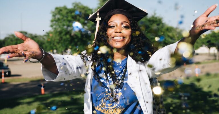 Pesquisador celebrando marco acadêmico com documentos e laptop em ambiente profissional
