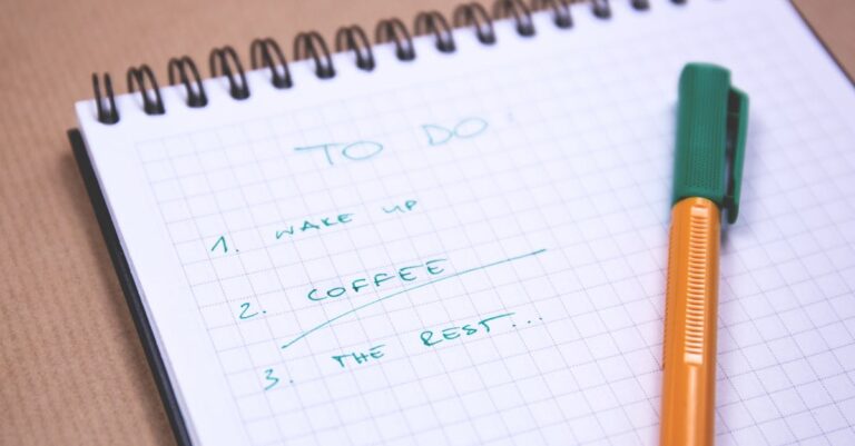 Mulher escrevendo lista de etapas de projeto em caderno sobre mesa organizada