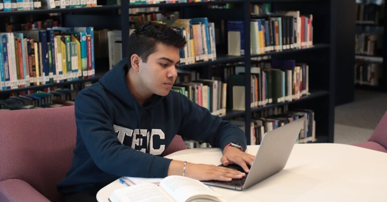 Doutorando marcando checklist de sucesso em pesquisa quantitativa com laptop ao fundo