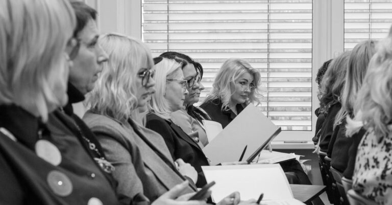 Grupo de acadêmicos em discussão séria ao redor de mesa em sala iluminada