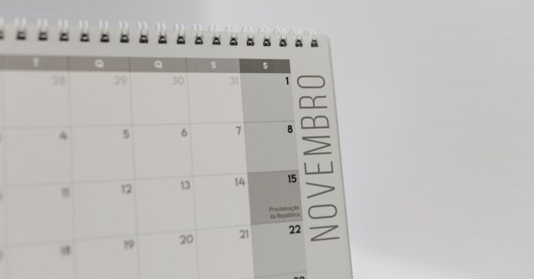 Mesa de trabalho limpa com calendário acadêmico, relógio e notebook aberto, fundo claro e iluminação natural