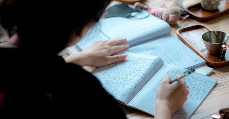 Estudante lendo jornal acadêmico com foco em mesa organizada e fundo claro
