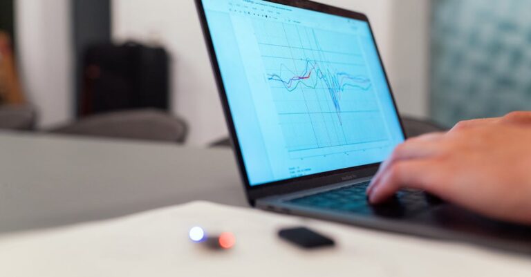 Pesquisador detalhando análise de dados e estatísticas em laptop com gráficos visíveis