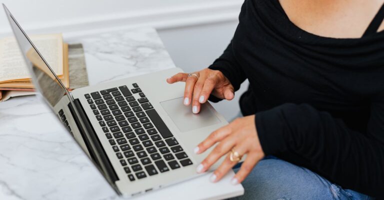 Mulher concentrada digitando em laptop em home office minimalista, com plantas e luz natural.