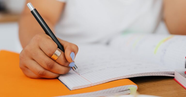 Estudante de pesquisa documentando metadados em caderno ao lado de computador com iluminação natural