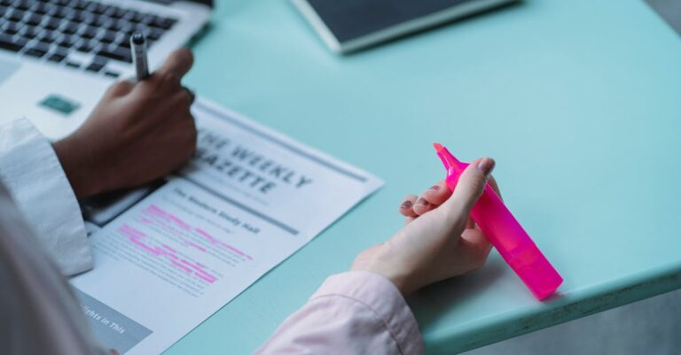 Estudante fazendo anotações em artigos científicos em notebook sobre escrivaninha minimalista