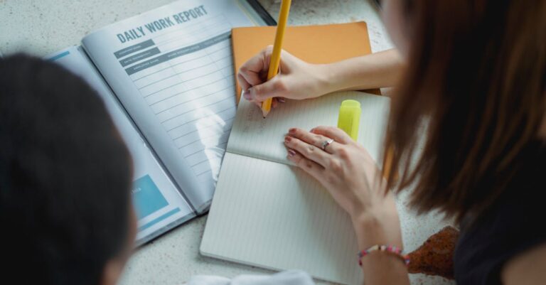 Estudante pesquisadora planejando pesquisa com anotações e laptop em ambiente minimalista