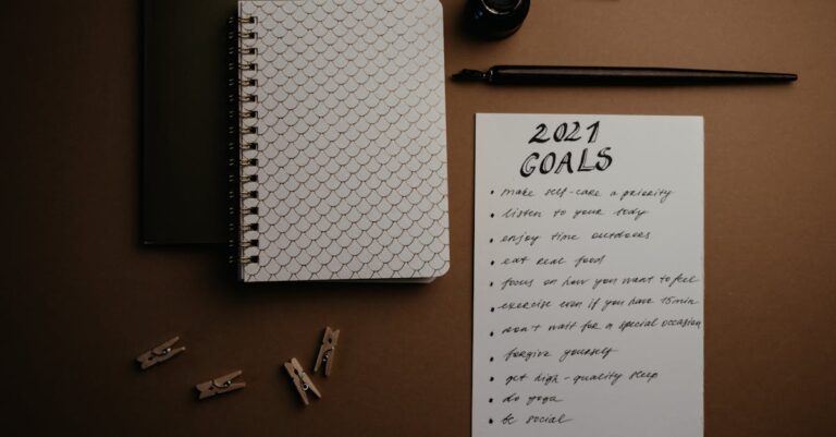 Analista anotando premissas sensíveis em caderno ao lado de computador com gráficos, fundo limpo