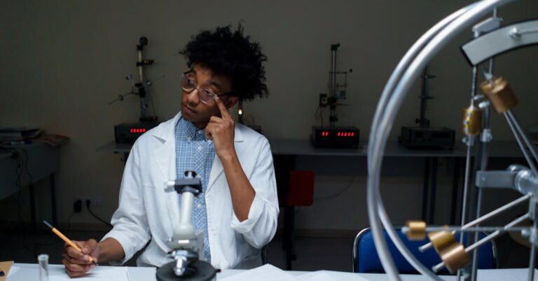 Estudante de doutorado organizando e sintetizando pilha de artigos científicos em mesa clean