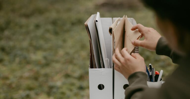 Mãos organizando pastas de arquivos acadêmicos em superfície limpa e iluminada