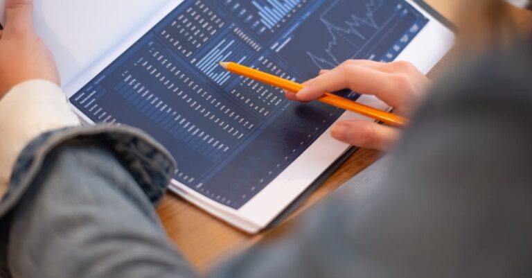 Pesquisador sério revisando anotações em caderno sobre análise de dados, mesa limpa com laptop ao fundo.