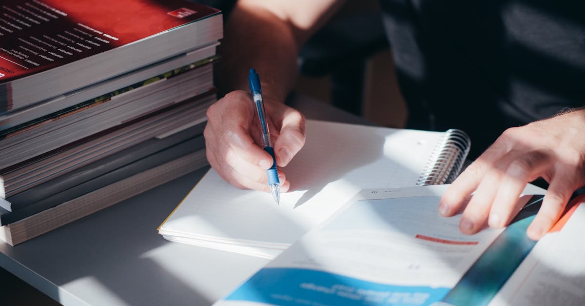 Pesquisador concentrado escrevendo em notebook sobre mesa clara com iluminação natural
