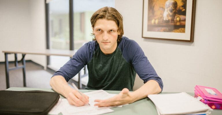 Estudante universitária frustrada revisando papéis de tese com marcações vermelhas em escritório claro