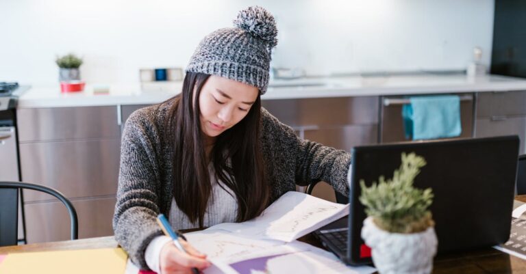 Estudante de pesquisa compilando estatísticas e gráficos em laptop em ambiente de escritório minimalista