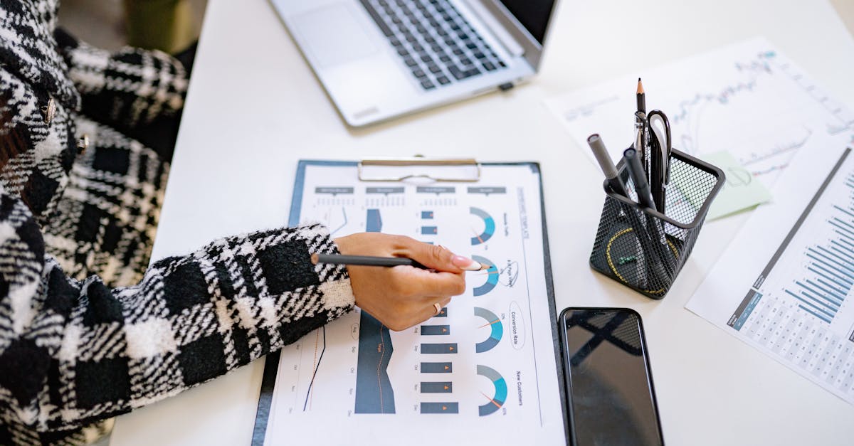 Pesquisador focado analisando gráficos estatísticos e pressupostos em laptop sobre mesa clean com iluminação natural