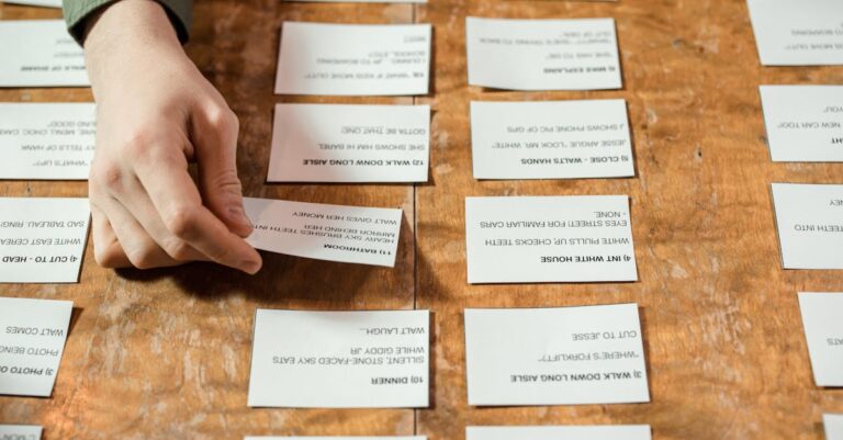 Mãos organizando papéis acadêmicos e documentos em mesa minimalista com iluminação natural