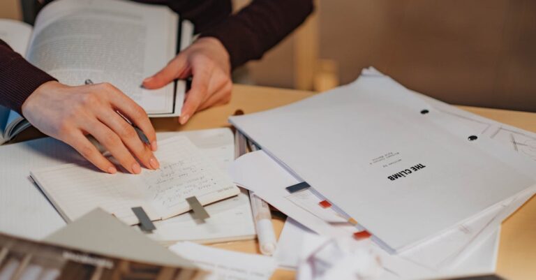 Doutorando escrevendo notas de metodologia em caderno ao lado de laptop em ambiente iluminado naturalmente