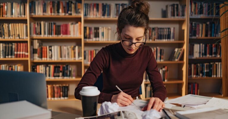 Mulher pesquisadora concentrada trabalhando em laptop em ambiente acadêmico clean