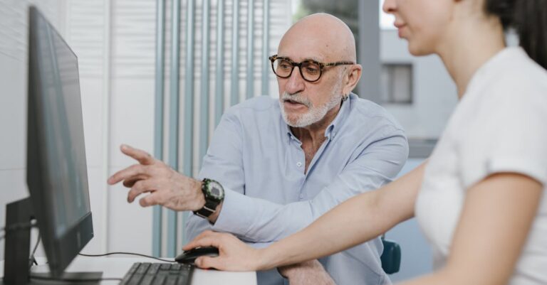 Orientador e estudante discutindo academicamente em escritório iluminado naturalmente.