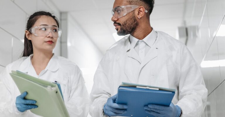 Cientista escrevendo conclusões em caderno com pilha organizada de papéis de pesquisa ao fundo