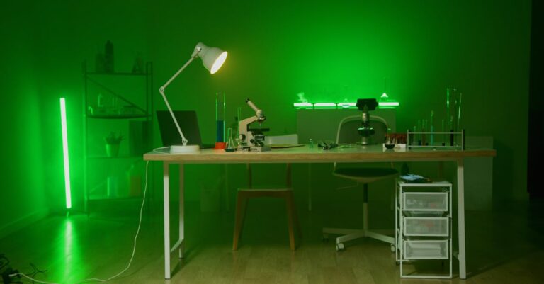 Pesquisador pensativo sentado em mesa clean com laptop e papéis acadêmicos