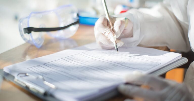 Pesquisador escrevendo hipóteses científicas nulas e alternativas em papel