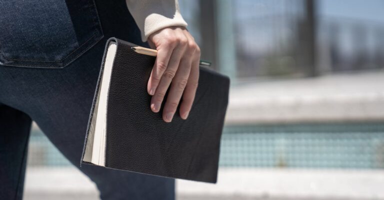 Caderno aberto mostrando passos numerados de plano com relógio e caneta em fundo neutro