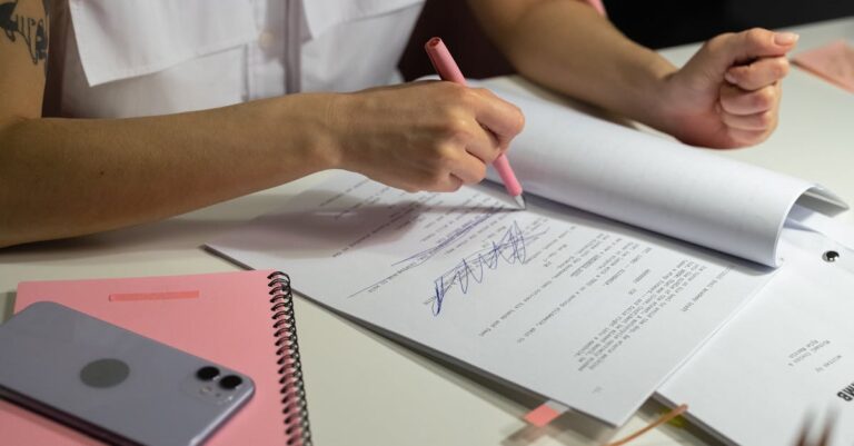 Pesquisadora verificando lista de verificação em caderno com laptop ao fundo