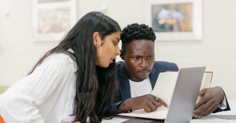 Professor e estudante discutindo perfis acadêmicos em mesa com laptop e papéis organizados