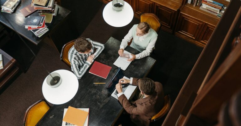 Pesquisadora escrevendo seção de discussão em laptop com anotações sobre implicações